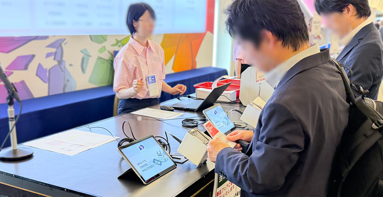 来場者が事前に印刷してきた入場証のQRコードをスキャナにかざして受付をしている様子