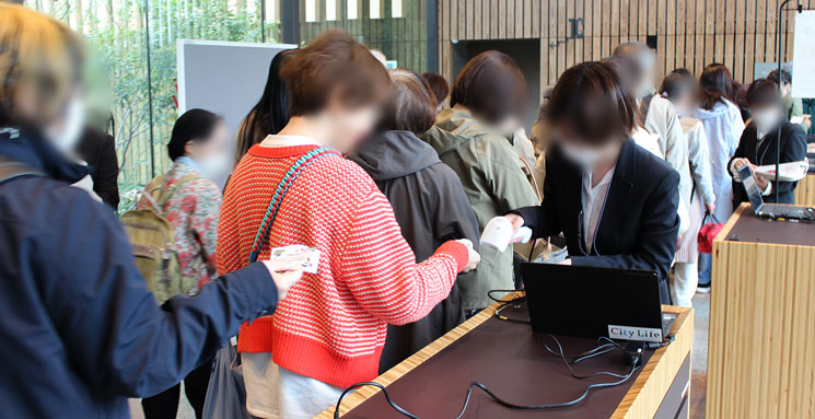 北摂文化大学の受付で来場者の会員証をスタッフがスキャナで読み取っている写真