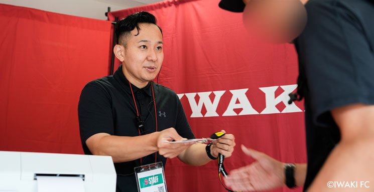 創立80周年イベントの受付にて、来場者が持参した入場証をスタッフがスキャンしている様子