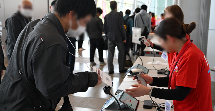 創立80周年イベントの受付にて、来場者が持参した入場証をスタッフがスキャンしている様子
