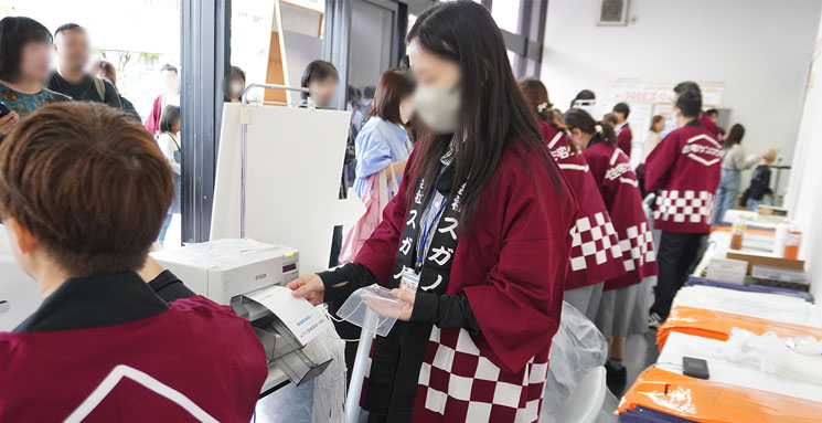 第11回住まいお宝発見フェアの会場入口で印刷された入場証（かみのぱす）をスタッフがターミナルスキャンしている様子