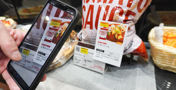 tohoグループ 総合展示商談会でスマートフォンでプライスカードのQRコードをスキャンしている様子