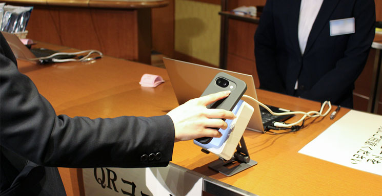 会場で来場者がスマホに表示したQRコードをスキャナにかざしている様子